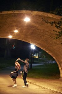 A couple dancing under a bridge