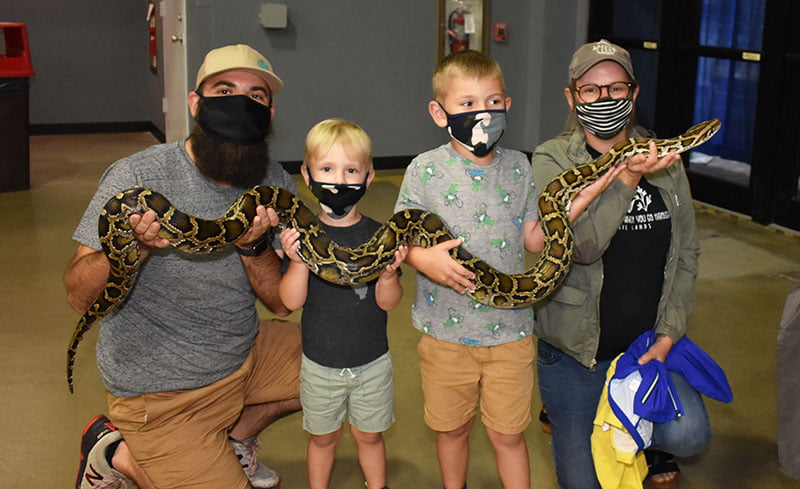 Image of family holding huge python