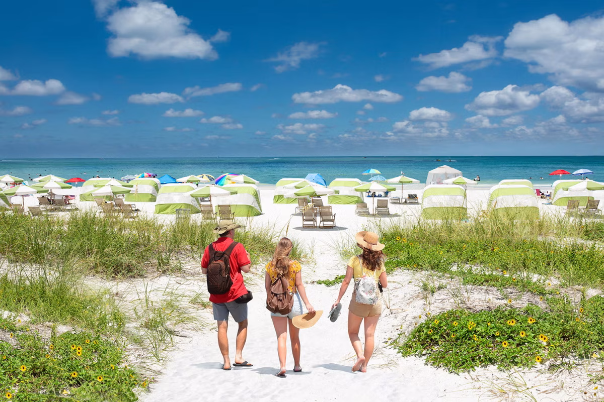 People walking onto beach towards ocean.