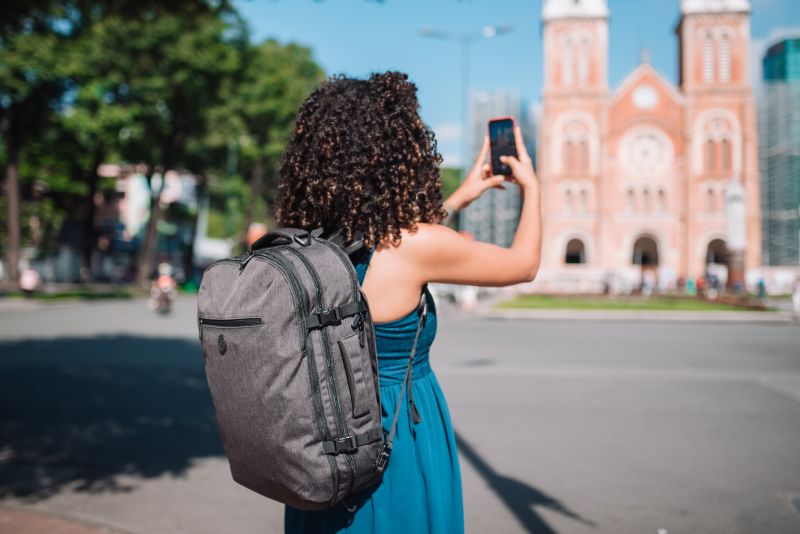 Woman with light luggage taking a photo while on the move. 
