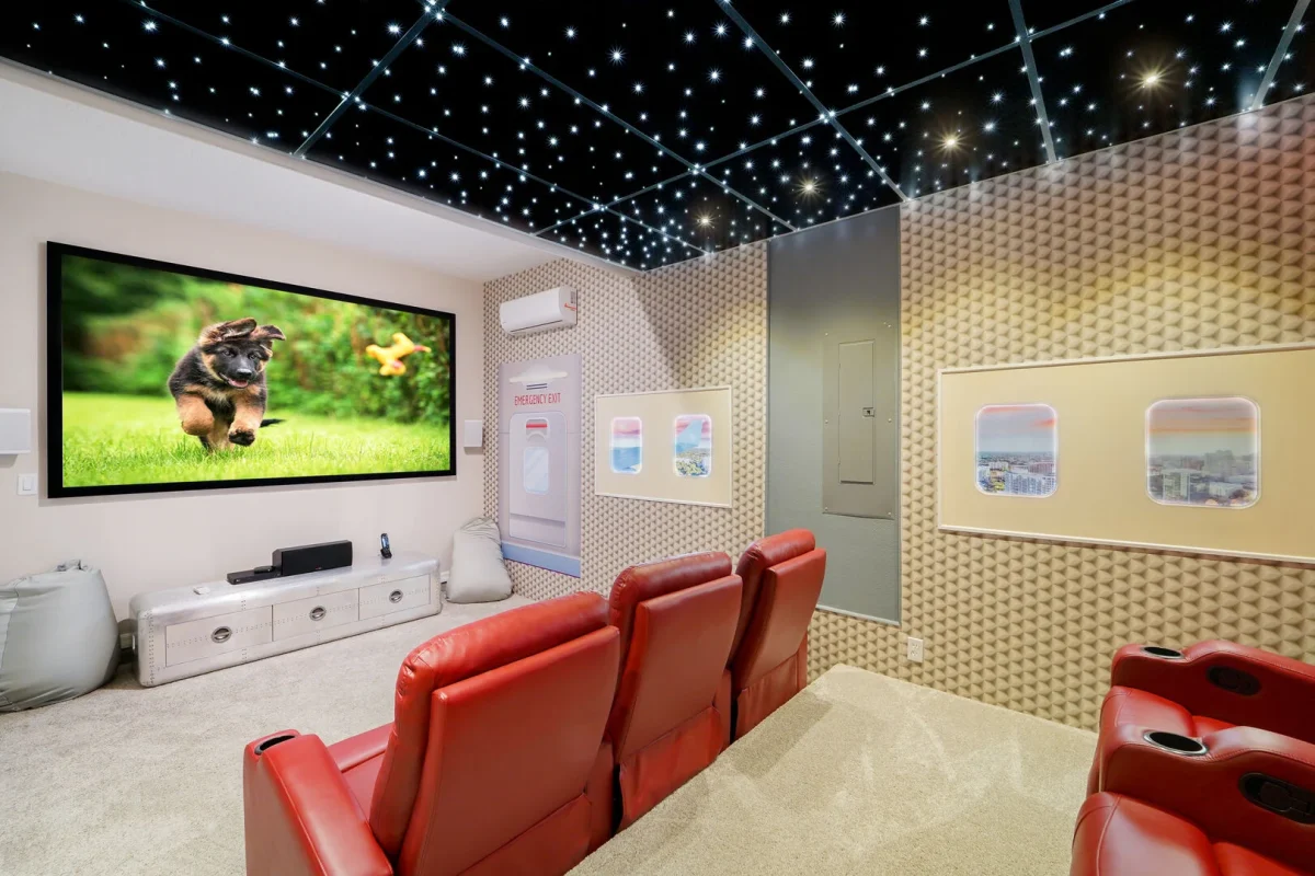 Private home theater with red reclining seats, large movie screen, and star-lit ceiling in an Orlando vacation rental. 