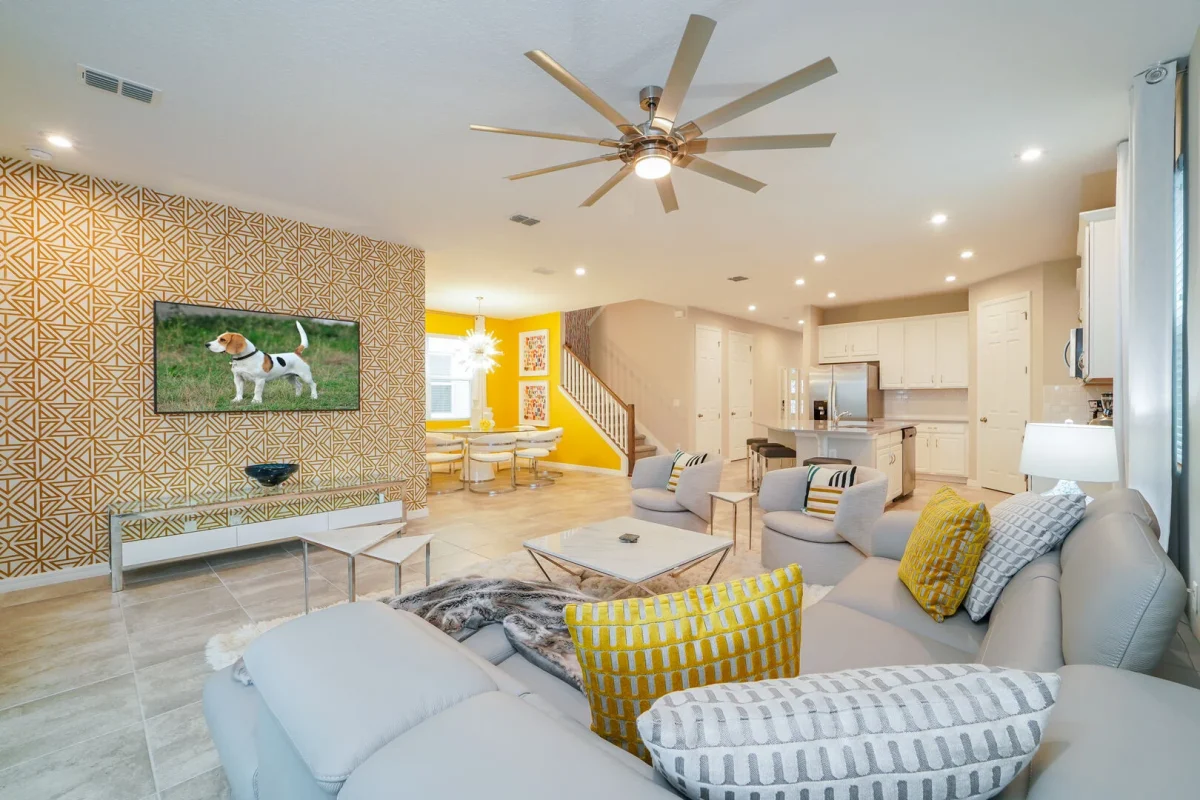Bright open-concept living area in an Orlando vacation rental featuring a modern living room, fully equipped kitchen, dining area, and stylish décor in a family-friendly Central Florida home near Disney. 
