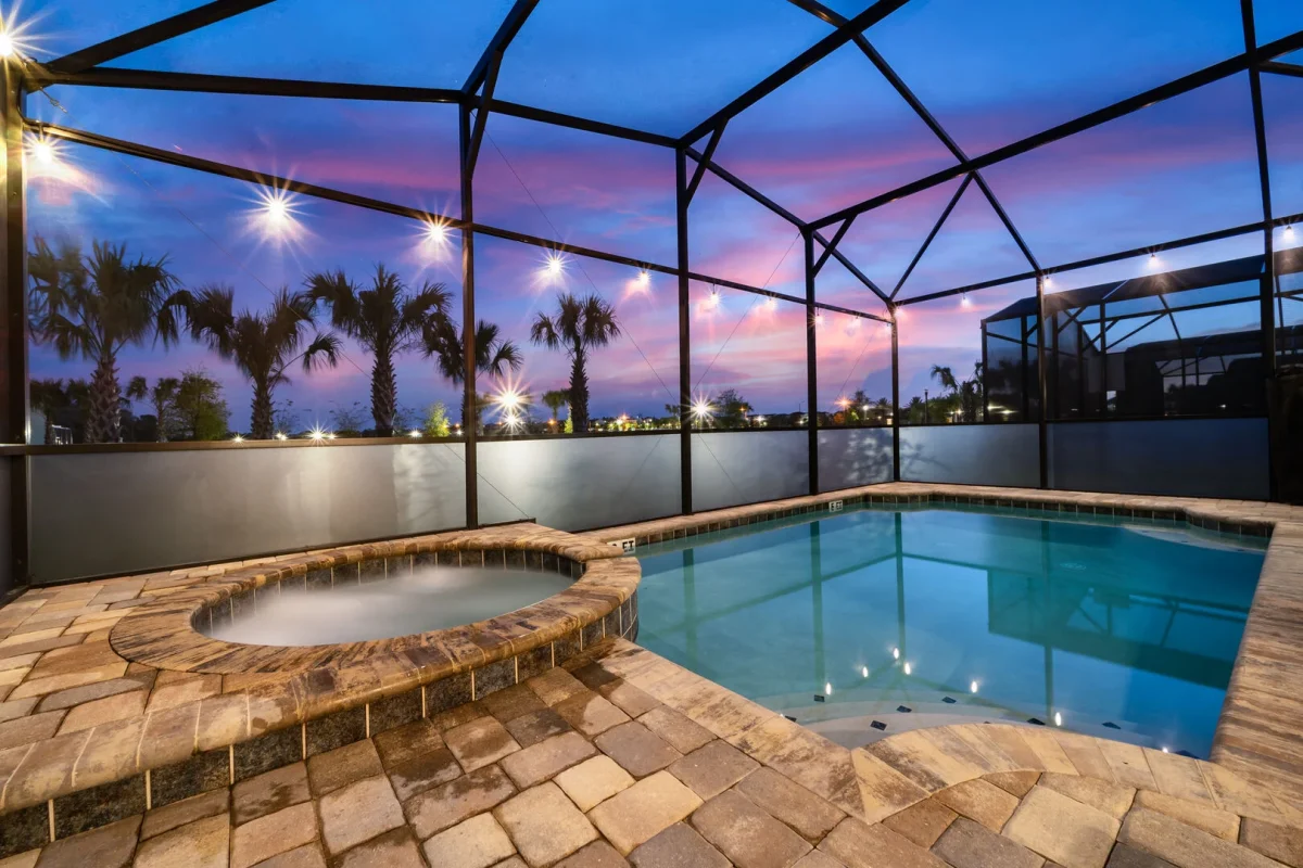 Screened private pool and spa illuminated at sunset with string lights at a Central Florida vacation rental in Orlando. 