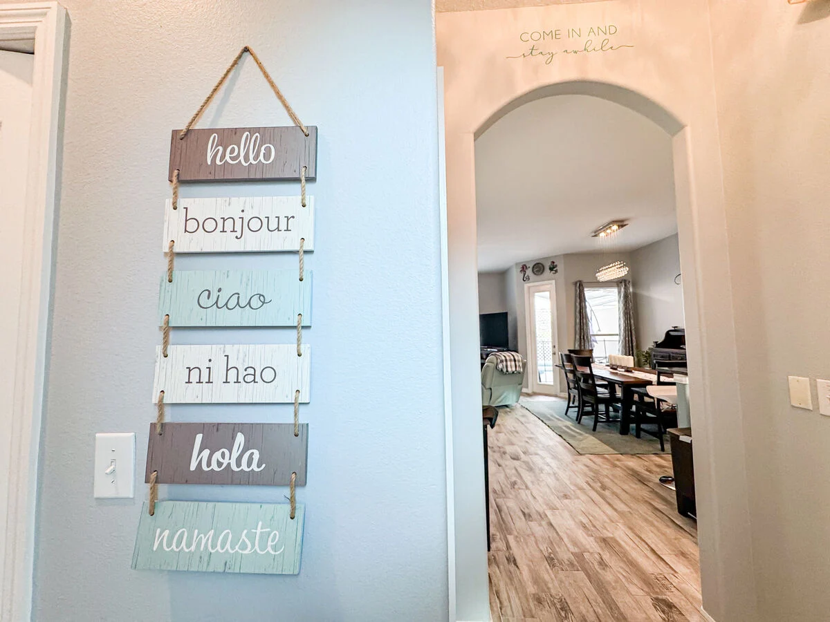 Welcoming entryway at an Orlando vacation rental featuring decorative multilingual wall art and open-concept view into living and dining area of a central Florida vacation home near Disney.