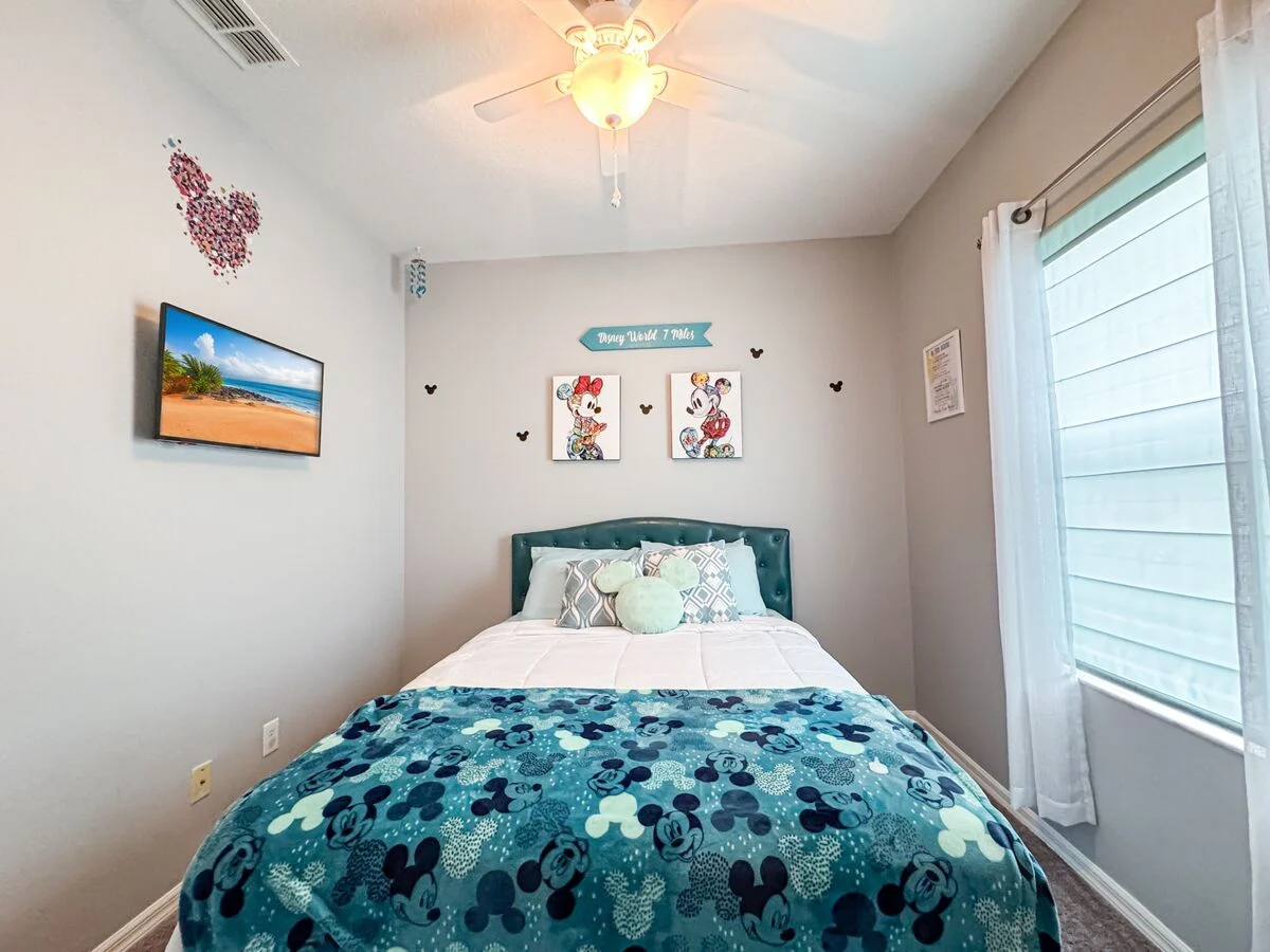 Disney-themed kids bedroom in an Orlando vacation rental featuring a cozy full bed, Mickey décor, ceiling fan, and bright natural light-perfect for families staying near Disney.