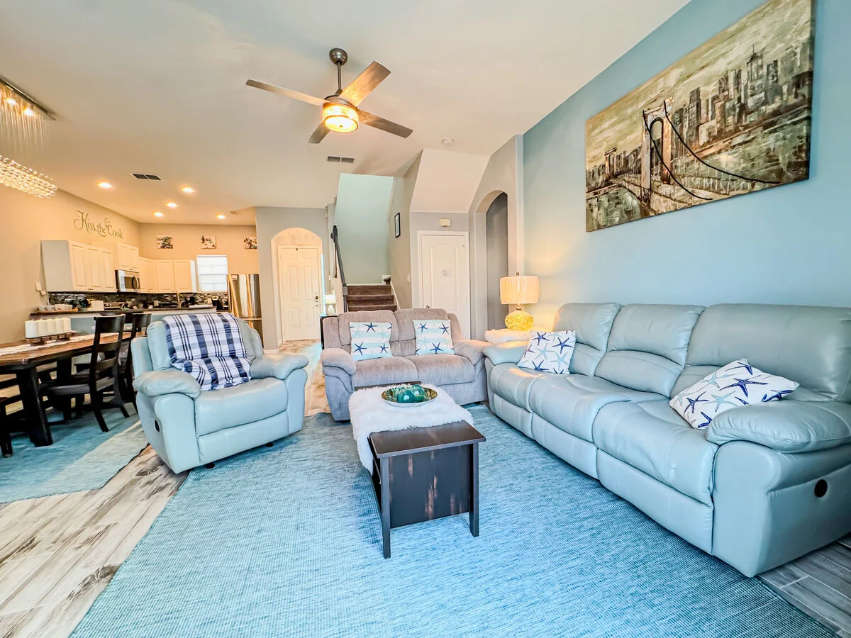 Open-concept Orlando vacation rental living room with comfortable seating, coastal décor, and a fully equipped kitchen-ideal for families staying near Disney.