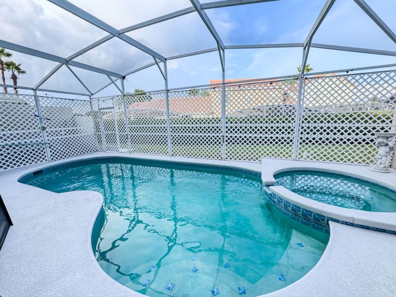Private screened-in pool and spa at an Orlando vacation rental, featuring a covered lanai and fenced backyard-ideal for relaxing after a day at Disney and Central Florida attractions.