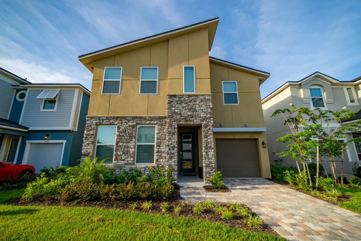 Modern two story vacation home in Central Florida with stone accents, private driveway, and landscaped front yard. 