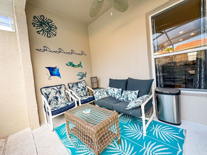 Covered patio seating area at an Orlando vacation rental with tropical décor, outdoor sofa and chairs-perfect for relaxing by the pool at a Central Florida vacation home near Disney.