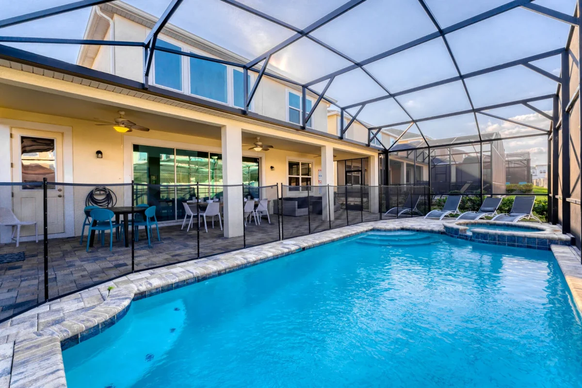 Spacious screened in pool and spa with child safety fence, sun loungers, and covered patio seating for outdoor relaxation.