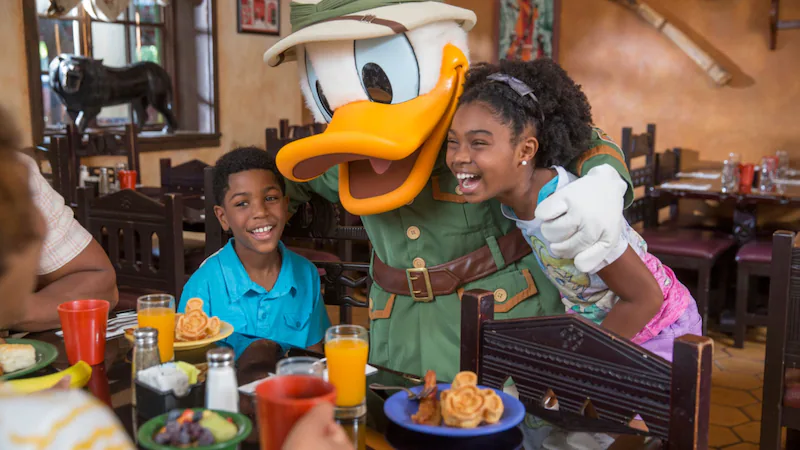 Donald duck hugging kids dining in Chef Mickeys character interaction restaurant.